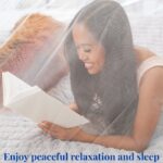 Woman reading on a bed with her dog beside her under a mosquito net