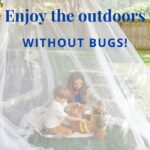 Mom and son under a mosquito net outside having a picnic.