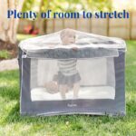 A baby boy with a teddy bear in a playpen outside covered with a Tedderfield baby mosquito net.